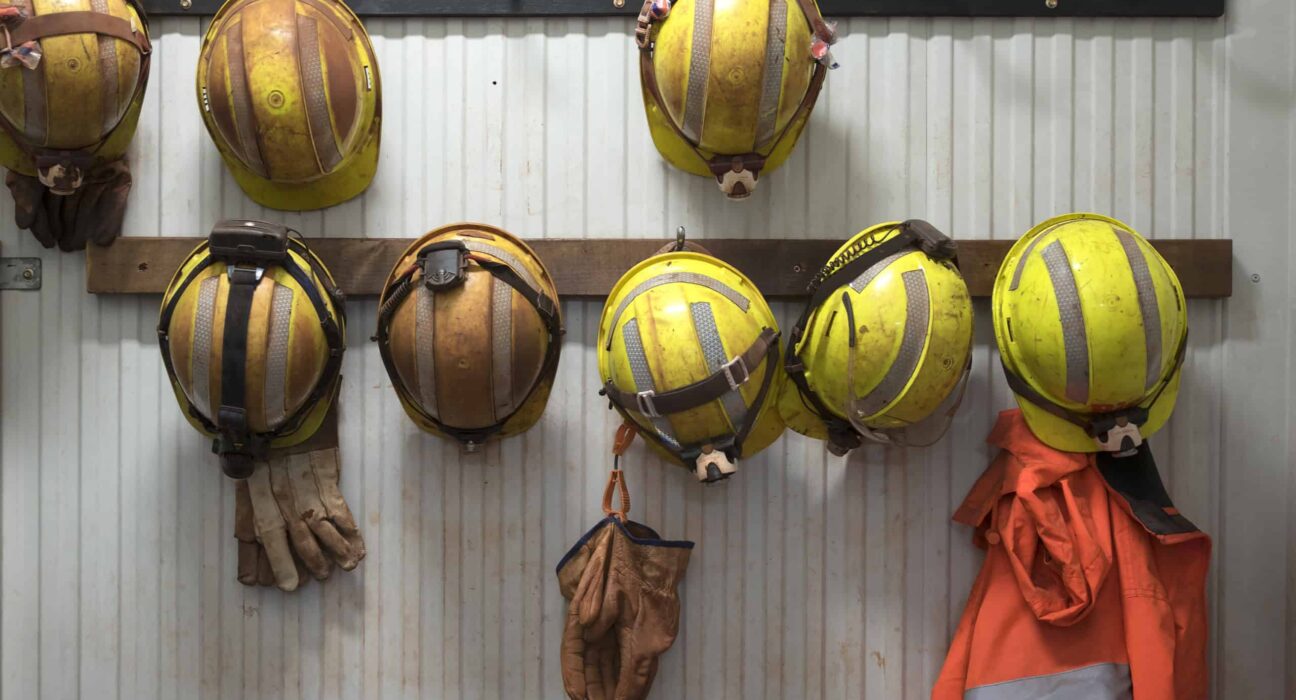 Safety helmets and gloves hang from a rack on a mining site.