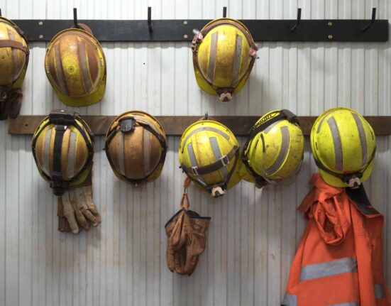 Safety helmets and gloves hang from a rack on a mining site.
