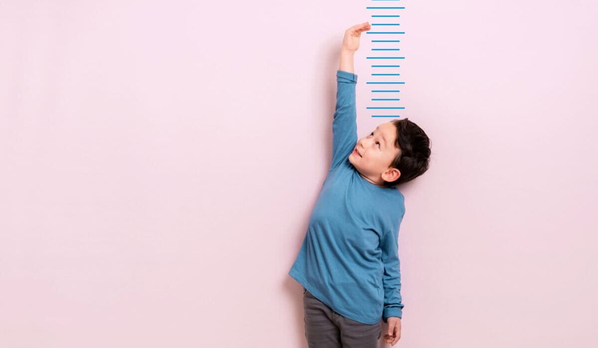 Child measures his height on wall. He is growing taller.