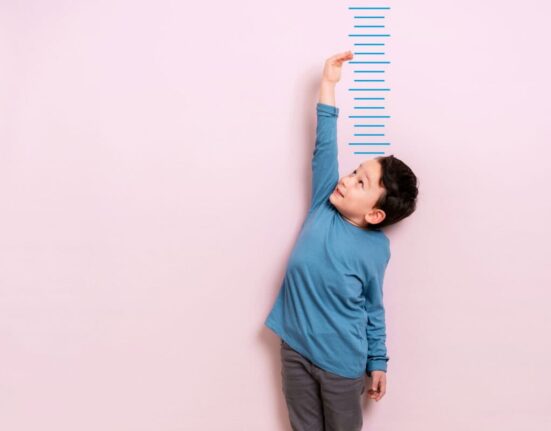 Child measures his height on wall. He is growing taller.