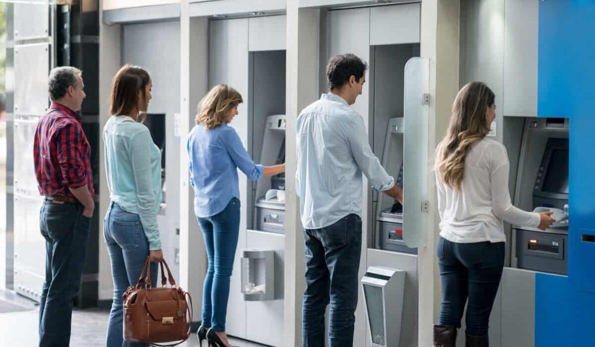 Group of people in a line at an ATM waiting to make a cash withdrawal