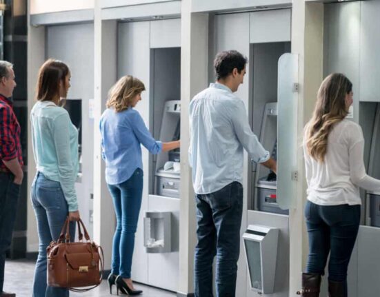 Group of people in a line at an ATM waiting to make a cash withdrawal